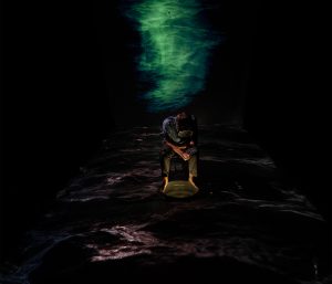 man sitting in wawes with dark surroundings