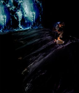 man sitting in wawes with dark surroundings