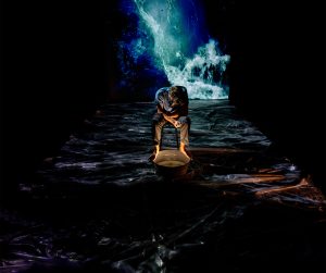 man sitting in wawes with dark surroundings