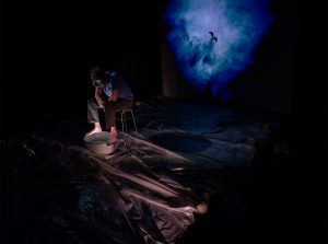 man sitting in wawes with dark surroundings