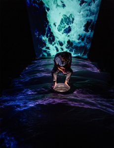 man sitting in wawes with dark surroundings