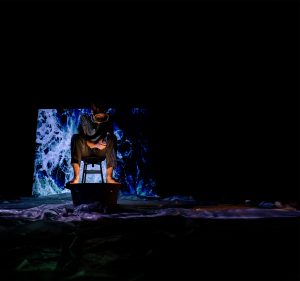 man sitting in wawes with dark surroundings