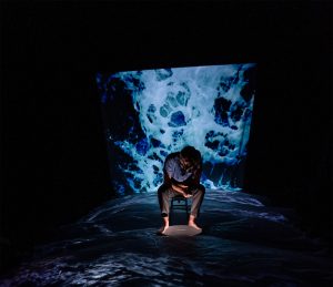 man sitting in wawes with dark surroundings