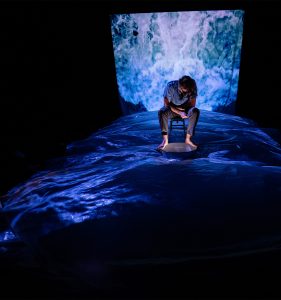 man sitting in wawes with dark surroundings