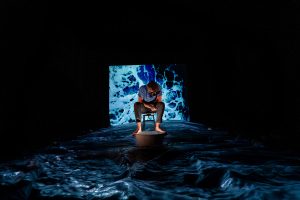 man sitting in wawes with dark surroundings