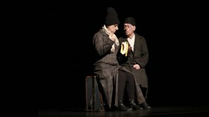 two clowns in black sitting on a suitcase