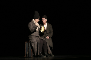 two clowns in black sitting on a suitcase