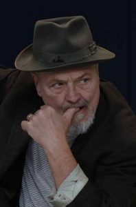 mand med hat bidder i sin tommelfinger