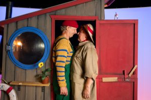 En mand og en kvinde klemt i en døråbning ind til et lille træhus fra forestillingen flaskepost med riddersalen - gæstespil på teatret gruppe 38