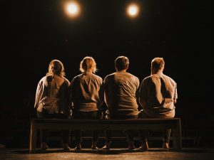 fire eprsoner sidder på bænk med ryggen til os