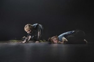 to personer henholdsvis ligger og kravler på mørkt gulv på foto fra danseforestillingen The Labyrinth