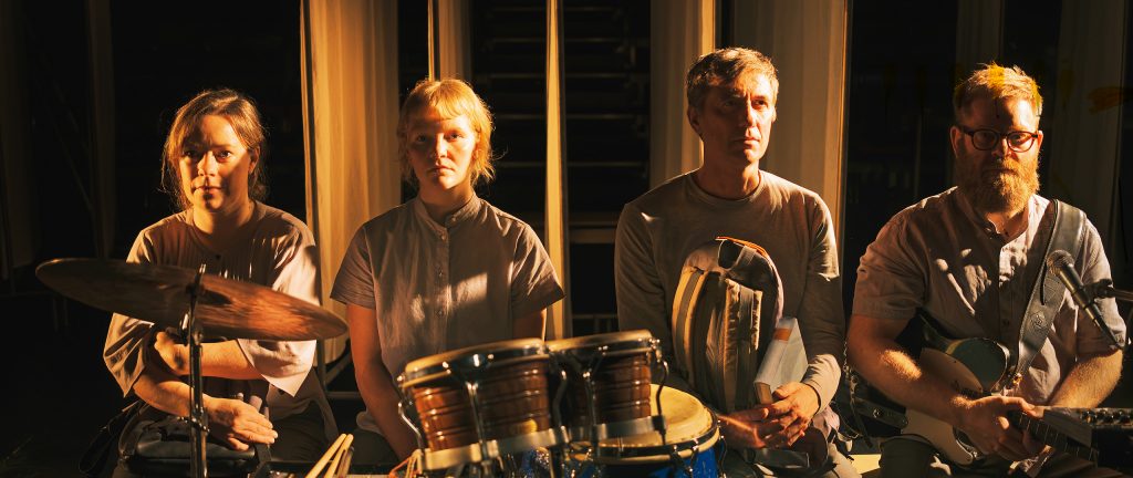 to kvinder og to mænd sidder ved siden af hinanden med trommer foran sig