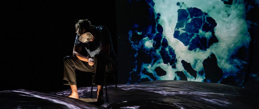 mand sidder med bare fødder i bølgehav med svømmebriller på - foto fra forestillingen Min søster er en havfrue, der er produceret af Teatret Gruppe 38 og teater Rum.